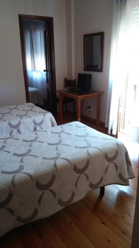Schlafzimmer mit einem Bett und einem Schreibtisch mit einem Computer in der Unterkunft Hotel El Sueve in Colunga