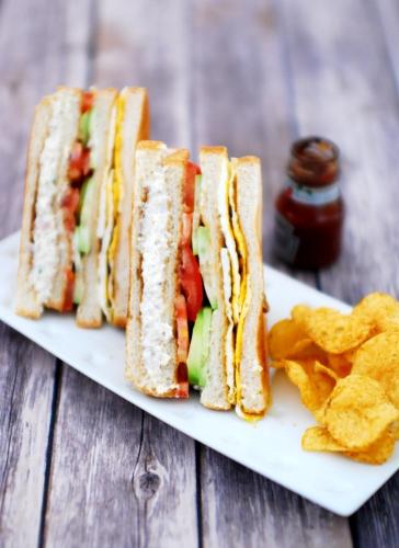 a plate with a sandwich and chips on a table at Hotel Royal Gardens Lahore in Lahore