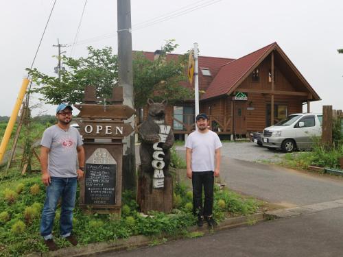 two men are standing in front of a sign at Pension Kamifuji in Osaki