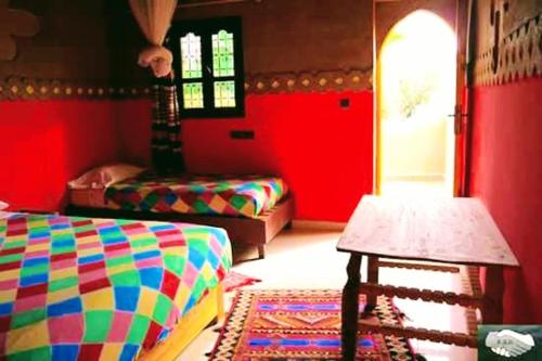 a colorful room with two beds and a table at d'hôte Jnane-Dar Diafa in Tamgrout
