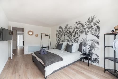 sypialnia z łóżkiem z malowidłem palmowym na ścianie w obiekcie L'appart w mieście Le Touquet-Paris-Plage