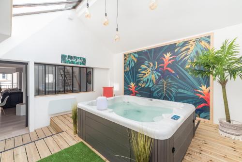a bath tub in a room with a tropical wallpaper at L'appart in Le Touquet-Paris-Plage