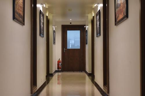 a hallway with a brown door and pictures on the walls at Heritage Inn in Mysore