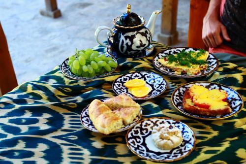 a table with plates of food and a teapot at Dervish Hostel in Bukhara