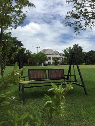 a park bench sitting in the grass in a field at Samerdrow Khao Yai in Mu Si