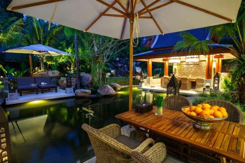 a pool with a table with a bowl of oranges on it at Villa on The Rocks, 4 bedrooms, Phuket in Surin Beach