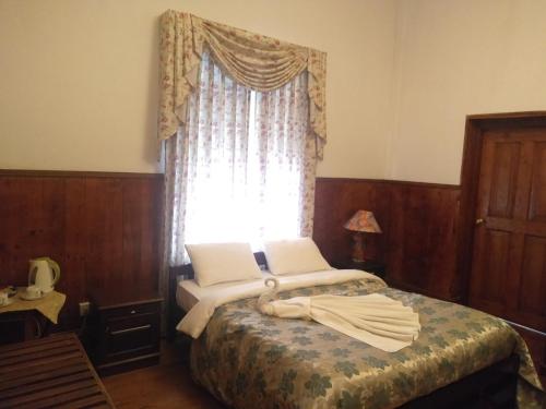 a small bedroom with a bed with a window at The Trevene Hotel in Nuwara Eliya