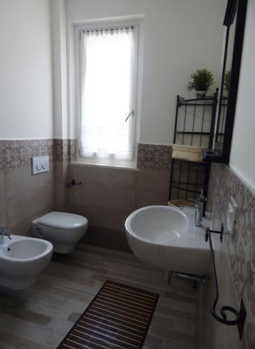 a bathroom with two sinks and a toilet and a window at Appartamento due sorelle in Sirolo