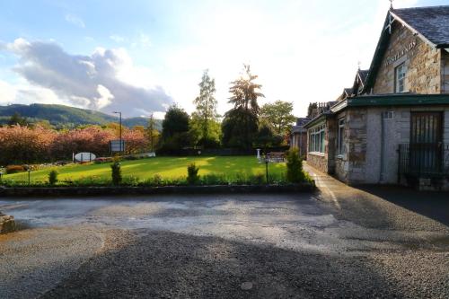 an empty street in front of a building with a yard at Westlands of Pitlochry in Pitlochry