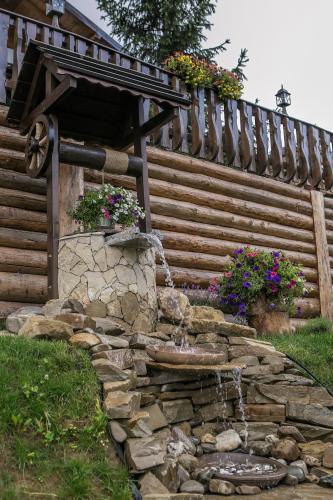 a stone fountain in front of a wooden building at Casa Verde in Voronet