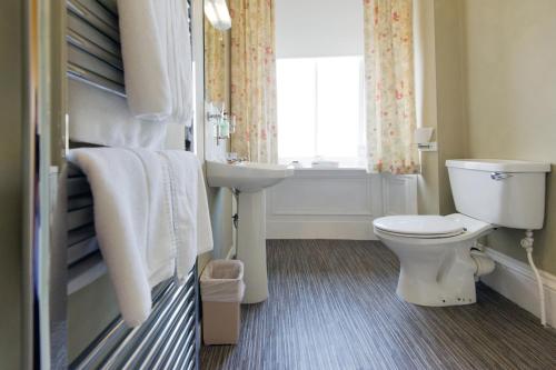 a bathroom with a toilet and a sink and a window at Station Hotel in Thurso