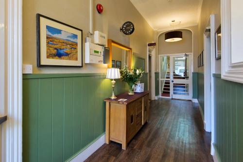 a hallway with green walls and a table with a lamp at Station Hotel in Thurso