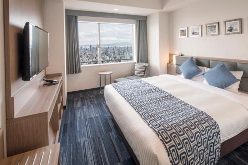 a hotel room with a bed and a flat screen tv at Art Hotel Osaka Bay Tower in Osaka