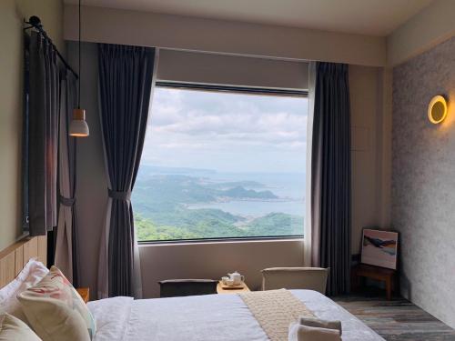 a bedroom with a large window with a view at Two Easy Inn in Jiufen