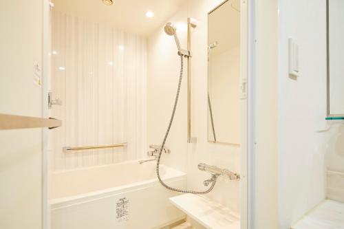 a white bathroom with a shower and a sink at Art Hotel Osaka Bay Tower in Osaka