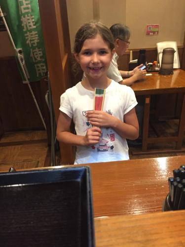 a young girl holding a toothbrush in front of a table at Guest house daisho oshiro asobi in Matsue