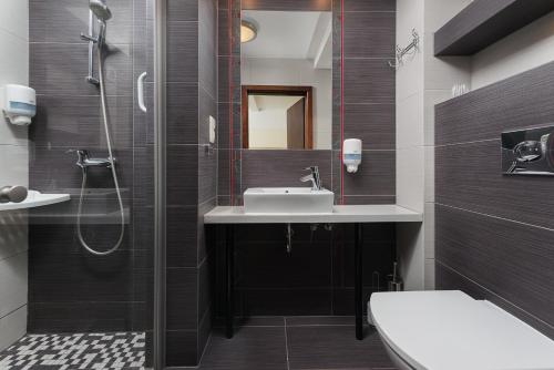 a bathroom with a shower and a sink and a toilet at Hotel Willa Złota in Karwia