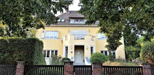 a yellow house with a fence in front of it at Villa Romahn in Schkeuditz