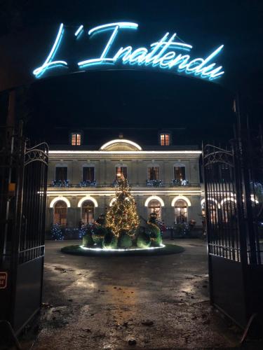 ChaunyにあるL’inattenduのネオンの看板のある建物前のクリスマスツリー