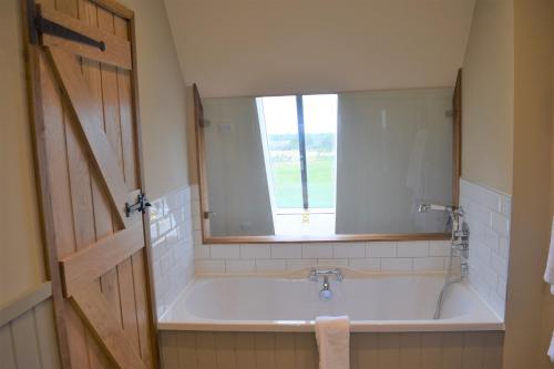 a bathroom with a bath tub with a window at The Plough Inn in Stalisfield