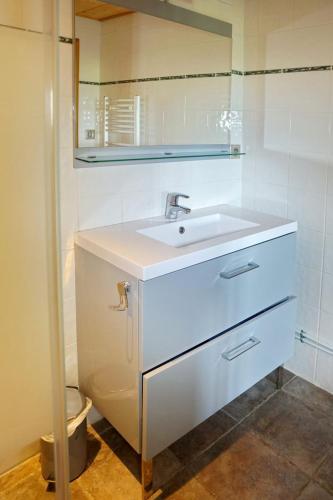 une salle de bain blanche avec un lavabo et un miroir dans l'établissement chalet la Louvière, à La Toussuire