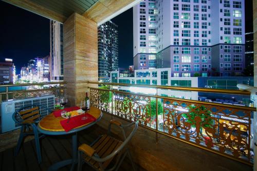 einen Tisch und Stühle auf dem Balkon mit Blick auf die Skyline der Stadt in der Unterkunft BOLTON Hotel in Gwangju