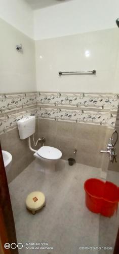 a bathroom with a toilet and a red bucket at MAYUR paying Guest house in Varanasi
