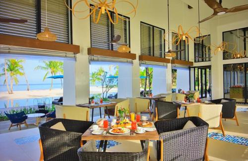 a restaurant with a table and chairs and the beach at Pullman Maldives Maamutaa - All-Inclusive Resort - 50 percent off Transfers in Maamutaa