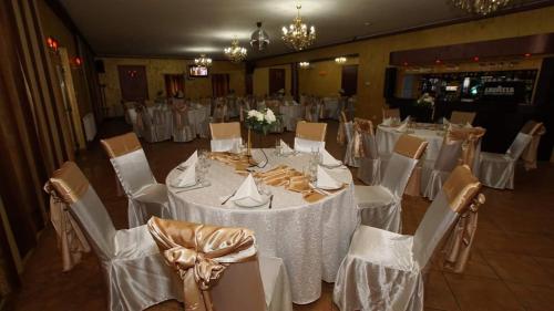 une salle de banquet avec des tables blanches et des chaises blanches dans l'établissement Pensiunea Gallamar, à Bîrlad