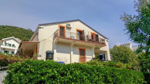 a white house with a balcony and trees at Baka Zlata Apartments in Petrovac na Moru