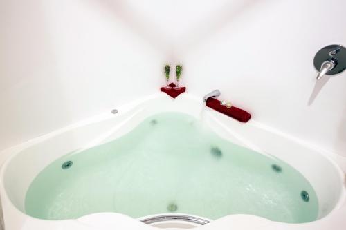 bañera blanca con grifo rojo en Settlers Boutique Motel, en Hanmer Springs