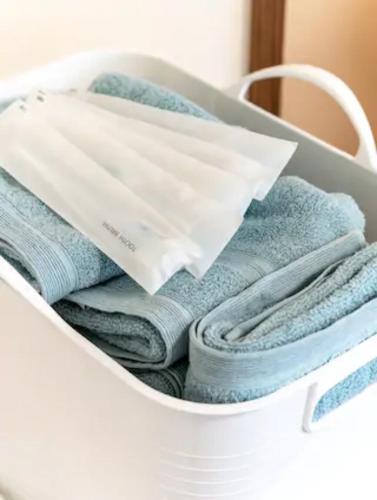 a white laundry basket filled with towels at 隠れ宿ＴＯＭＡＲo in Motobu