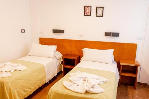 two beds in a room with white sheets at Hotel Ramos Mejía in Mar del Plata