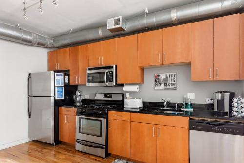 a kitchen with wooden cabinets and stainless steel appliances at Trendy Castleberry Hill Condo- Walk to Mercedes Benz/ All Downtown Attractions in Atlanta
