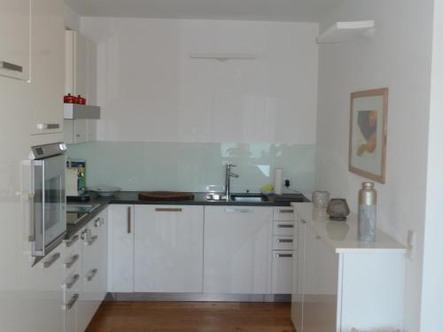 una cocina con armarios blancos y fregadero en Weisse Villa en Millstatt