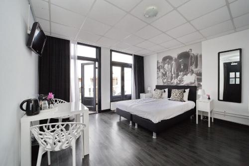 1 dormitorio con 1 cama, mesa y sillas en Hotel Zeespiegel en Zandvoort