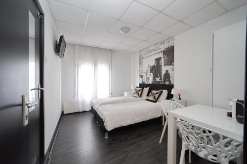 - une chambre blanche avec un lit, une table et un bureau dans l'établissement Hotel Zeespiegel, à Zandvoort
