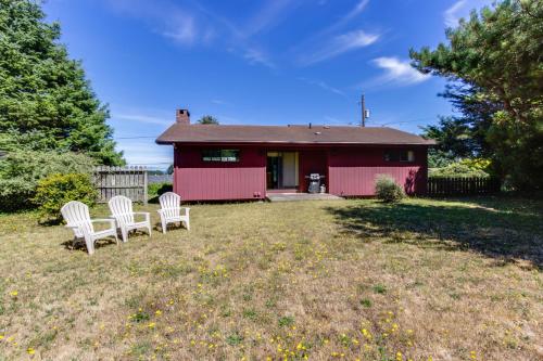 a red house with two white chairs in the yard at The Eagle's Nest in Lincoln City