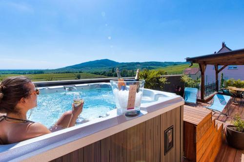 a woman in a hot tub with drinks in it at Le Panoramic & Spa in Itterswiller