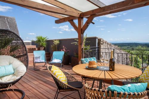 a patio with a wooden table and chairs on a deck at Le Panoramic & Spa in Itterswiller