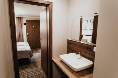 een badkamer met een wastafel, een spiegel en een bed bij Villa Paula in Polanica-Zdrój