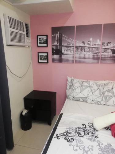 a bedroom with a bed and a pink wall at Nica's Place Property Management Services at Horizons 101 Condominium in Cebu City
