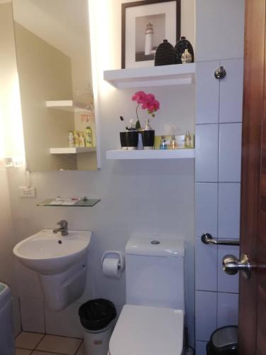 a white bathroom with a toilet and a sink at Nica's Place Property Management Services at Horizons 101 Condominium in Cebu City