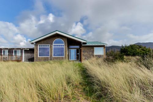 a house in the middle of a field of tall grass at Beach Whale in Rockaway Beach