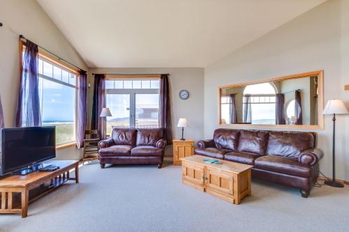 a living room with leather couches and a flat screen tv at Beach Whale in Rockaway Beach