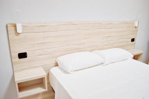 a bedroom with a white bed with a wooden headboard at Miu Hotel in Milan
