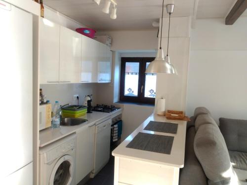 uma cozinha com armários brancos, um lavatório e um sofá em Apartamento Ismael em Gausach