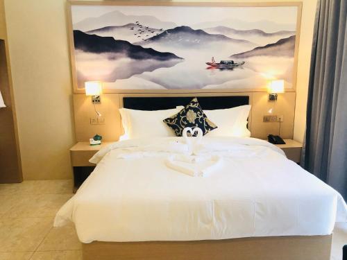 a bedroom with a large white bed with a painting at Season Inn Hotel in Barka