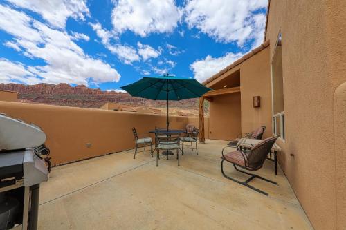 a patio with a table and chairs and an umbrella at Rim Village T2 in Moab
