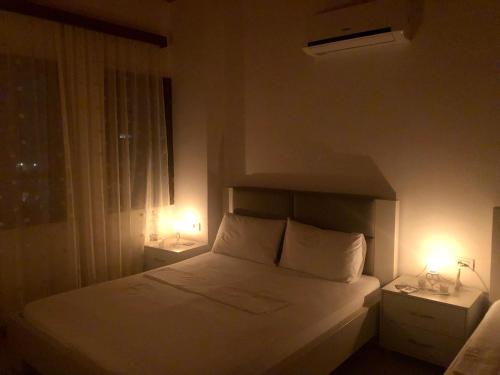 a bedroom with a white bed with two lights on it at Dhimitri's guest house in Berat